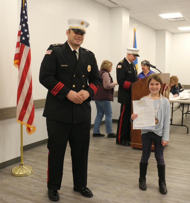 Milton Elementary second-grader Fiona Esposito is all smiles receiving her third-place award from MFD President Brian Reynolds Jr.